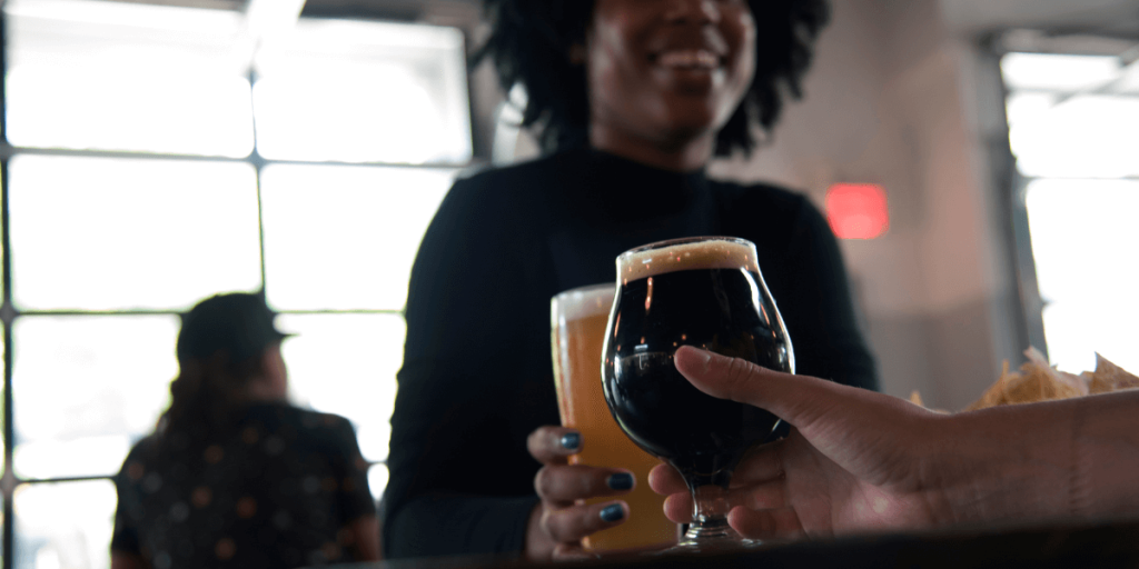 person holding glass of dark beer