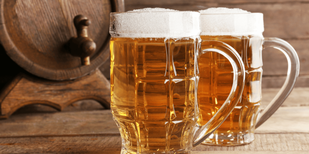 glasses of beer with barrel in the background