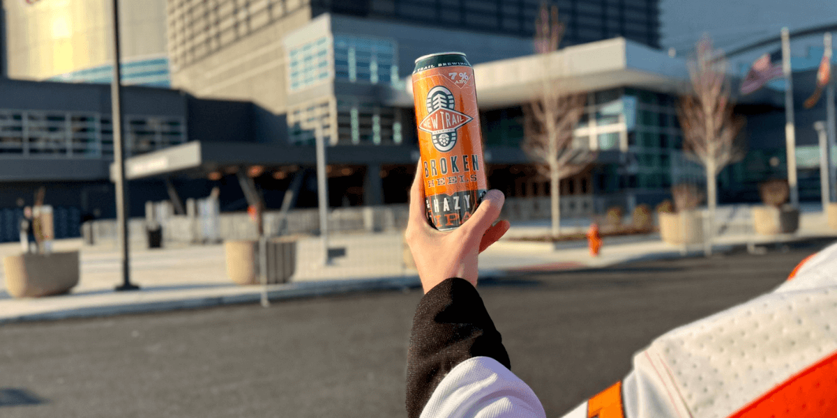 person holding up a New Trail Broken Heels IPA can